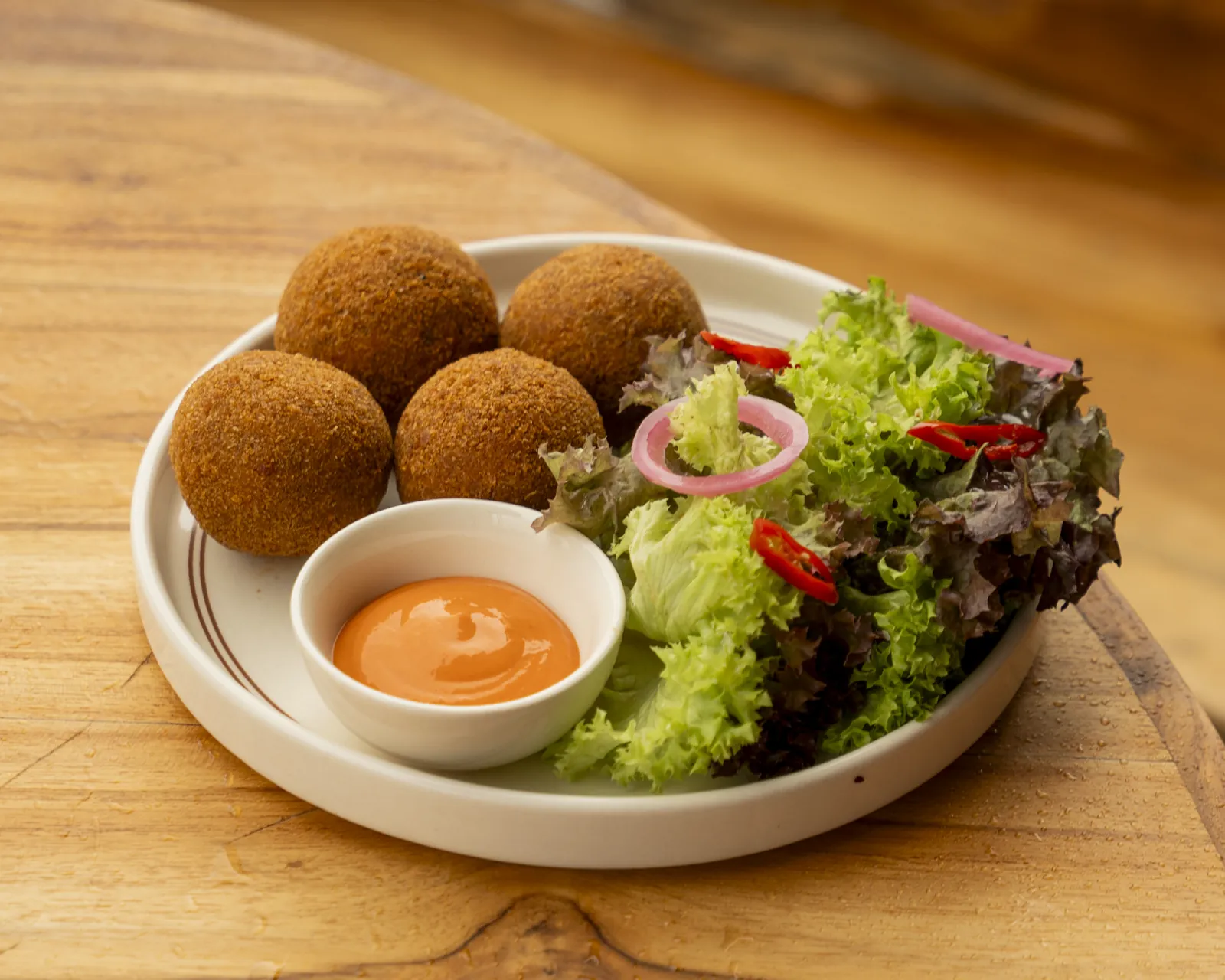 Golden croquettes with a dressed salad and dipping sauce at Nava