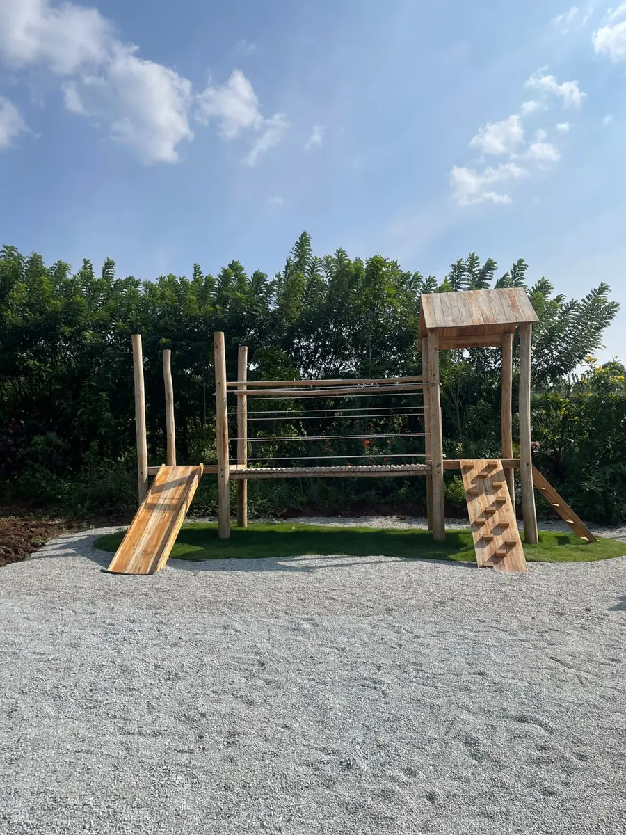A timber adventure frame with ramps, a rope-and-bar crossing and a small lookout