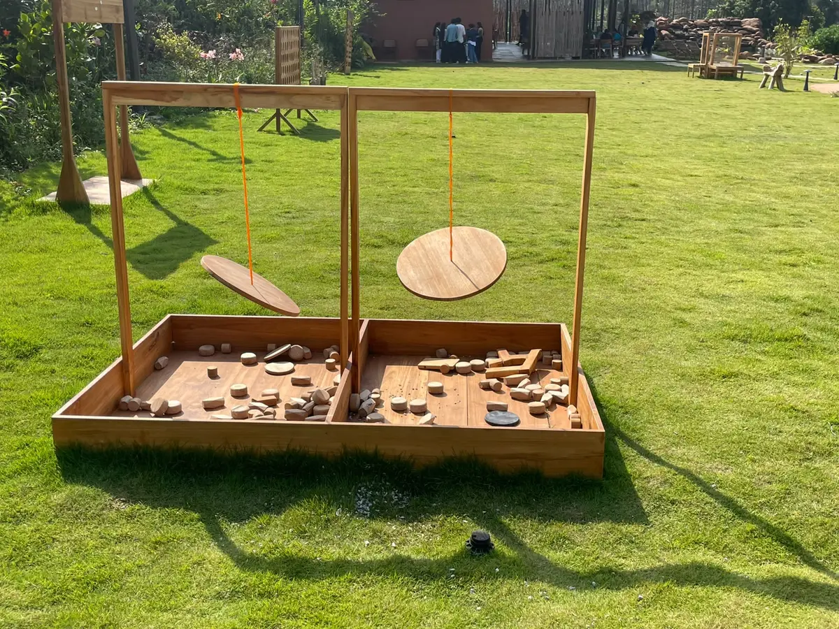 A timber sandpit with hanging balance discs, set on the lawn
