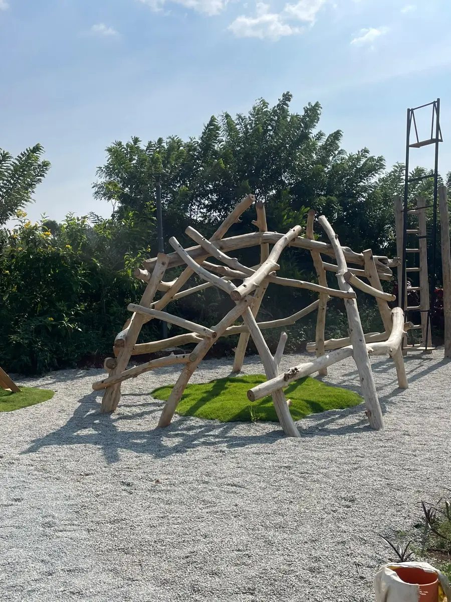 A climbing dome built from weathered branches on soft gravel