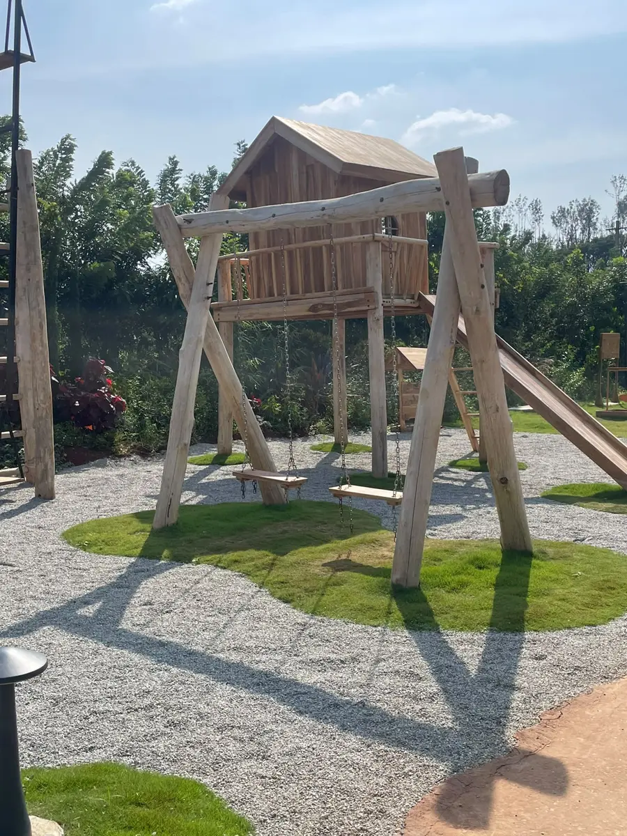Wooden swings hung beneath a treehouse, with a slide beside them